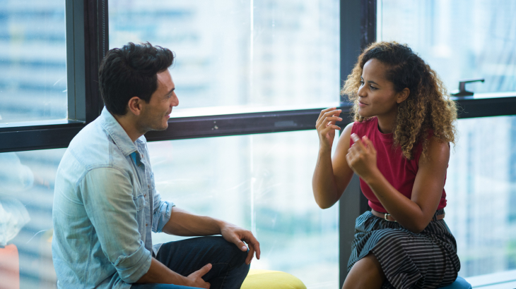 Homem e mulher sentados em um banco conversando