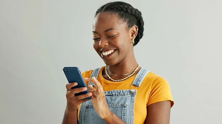 Mulher olhando para o celular e sorrindo