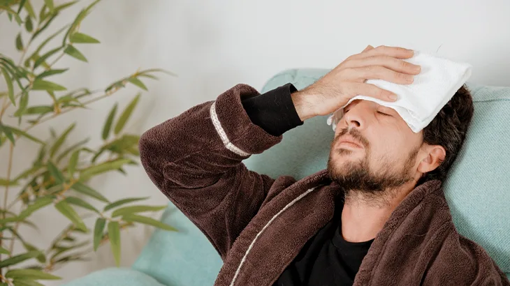 Homem deitado segurando um pano na cabeça