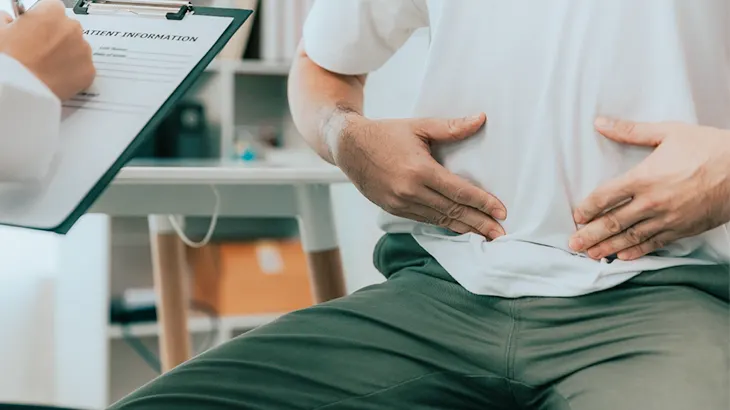 Homem com as duas mãos na barriga