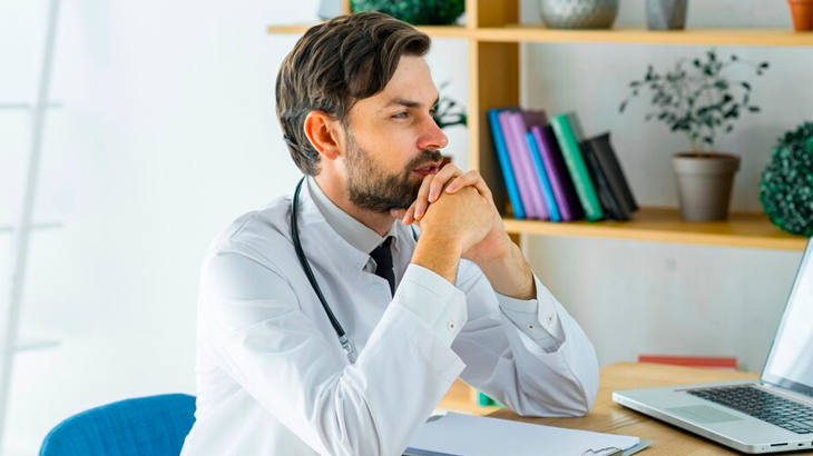 Médico sentado olhando para o computador