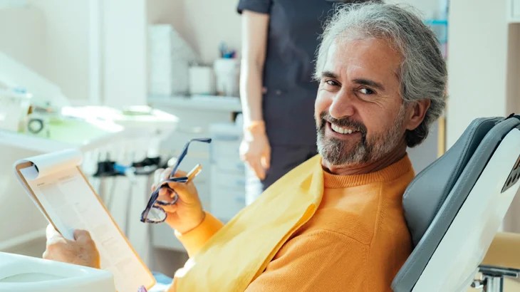 Homem na consulta odontológica, preenchendo uma ficha 