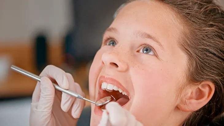 Menina com boca aberta para dentista