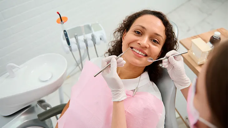 Mulher deitada na maca do dentista olhando para a dentista