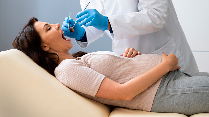 Mulher grávida deitada na maca do dentista 